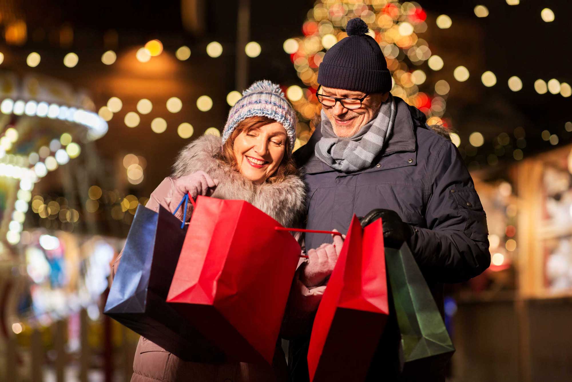 old couple at christmas market with shopping bags
